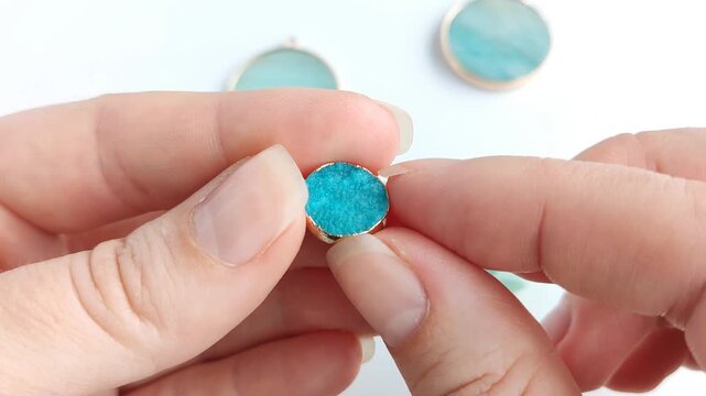 Two polished round gemstone pendants with natural turquoise patterns set in elegant gold bezels rest on a clean surface