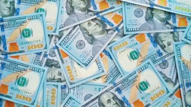 Top view full frame pattern of many hundred US dollar bills scattered on table. Background texture filled with 100 dollar cash notes concept for wealth, success, finance and prize lottery.