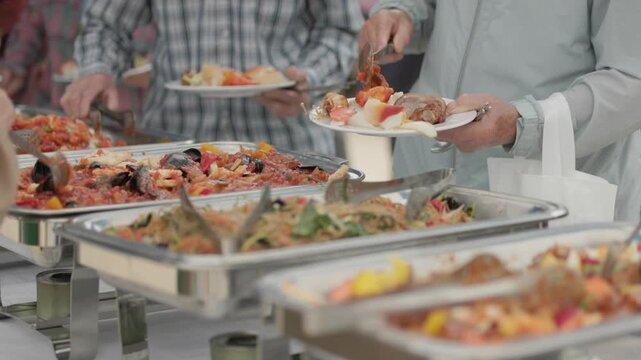 People serving food at an outdoor buffet