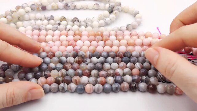 Colorful collection of polished natural gemstone round bead strands featuring grey, white, and pink mineral spheres displayed in parallel rows for jewelry design