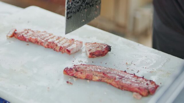 Cutting grilled meat with a cleaver at an outdoor food event