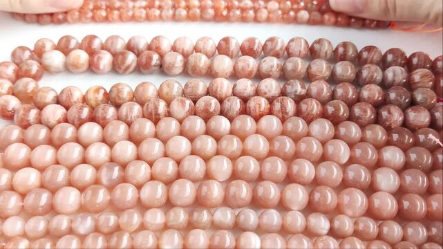 Faceted orange gemstone beads displaying shimmering mineral inclusions and polished surfaces arranged across multiple parallel threads for artisan jewelry projects