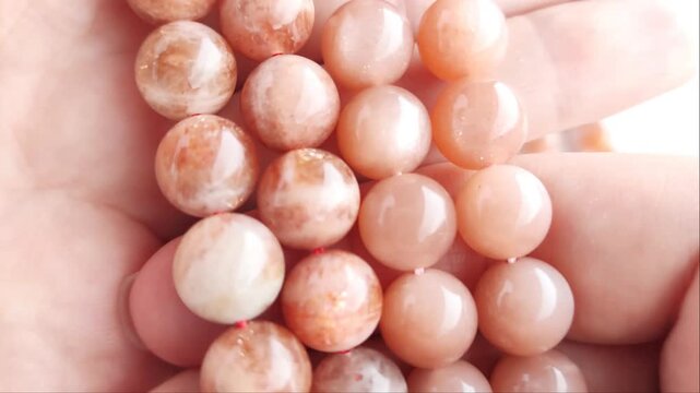 Faceted orange gemstone beads displaying shimmering mineral inclusions and polished surfaces arranged across multiple parallel threads for artisan jewelry projects