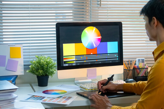 Closeup Graphic Designer Working at Desk with Color Wheel Swatches and Drawing Tablet in Modern Studio