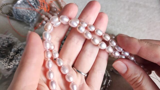 Collection of smooth pink pearl strands and natural gemstone beads arranged with metallic jewelry findings for artisan crafting projects