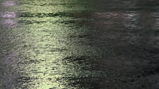 大雨に濡れて水たまりができた夜のアスファルト
