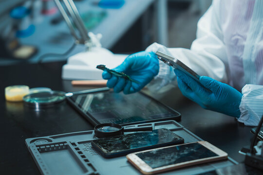 Technician Disassembling Mobile Phone with Precision Tools at Repair Workstation