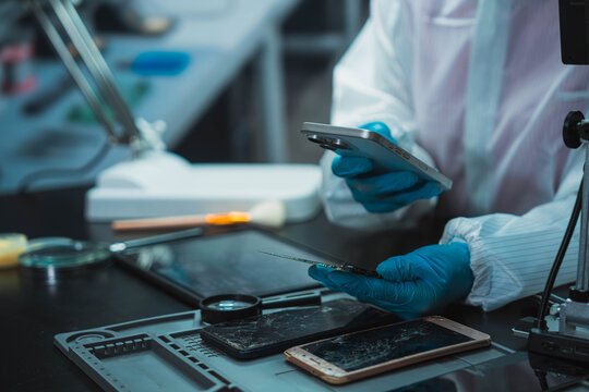 Technician Disassembling Mobile Phone with Precision Tools at Repair Workstation