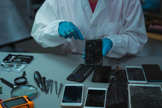 Technician Disassembling Mobile Phone with Precision Tools at Repair Workstation