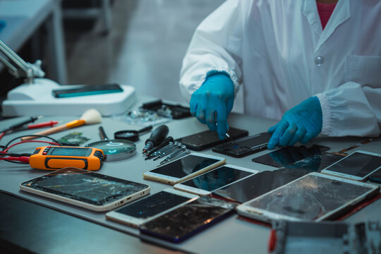 Technician Disassembling Mobile Phone with Precision Tools at Repair Workstation