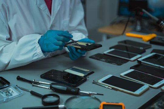 Technician Disassembling Mobile Phone with Precision Tools at Repair Workstation