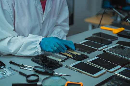 Technician Disassembling Mobile Phone with Precision Tools at Repair Workstation
