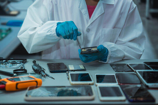 Technician Disassembling Mobile Phone with Precision Tools at Repair Workstation