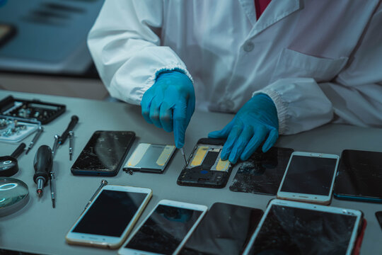 Technician Disassembling Mobile Phone with Precision Tools at Repair Workstation