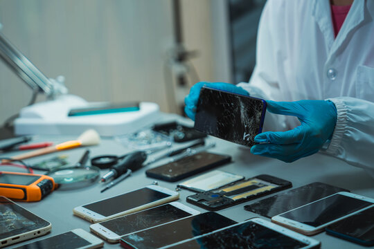 Technician Disassembling Mobile Phone with Precision Tools at Repair Workstation