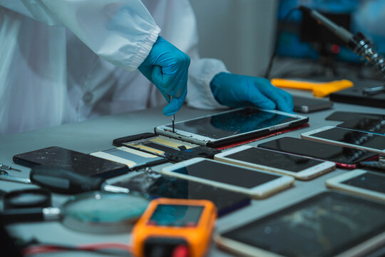 Technician Disassembling Mobile Phone with Precision Tools at Repair Workstation