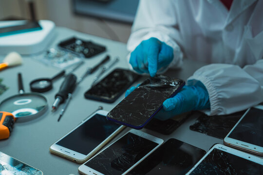 Technician Disassembling Mobile Phone with Precision Tools at Repair Workstation
