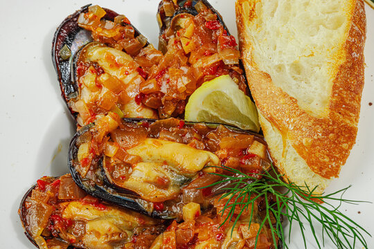 Mediterranean seafood concept. Mussels cooked in tomato salsa sauce with toasted bread, lemon, herbs