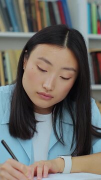 Student collecting information from different books, Asian girl in blue shirt gathering data for the paper. Self education concept.