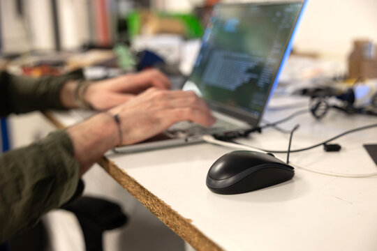 persona che lavora al computer portatile su una scrivania, utilizzando un mouse nero cablato