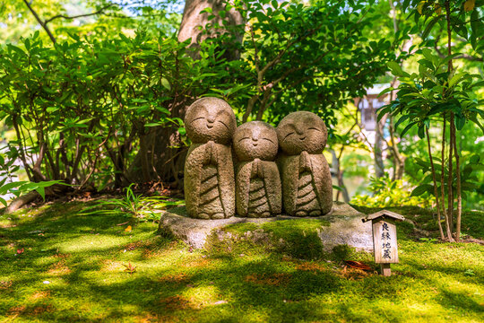 Cute stone Jizo statues in lush garden at Hase-dera temple in Kamakura Japan