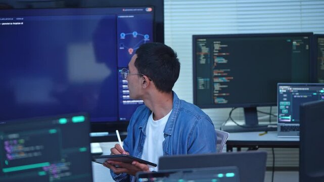 Focused programmer demonstrating coding techniques on a digital screen in a modern office environment