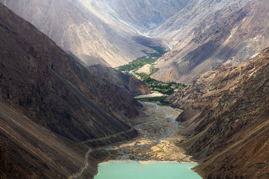 Aerial view of Satpara Lake nestled within the rugged, steep mountain ranges of the Karakoram, featuring turquoise glacial waters and a winding river valley in Skardu, Pakistan.