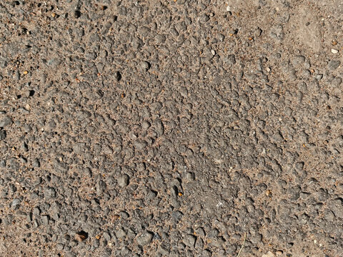 Textured ground surface showing rough materials and natural elements in an outdoor urban environment with copy space available