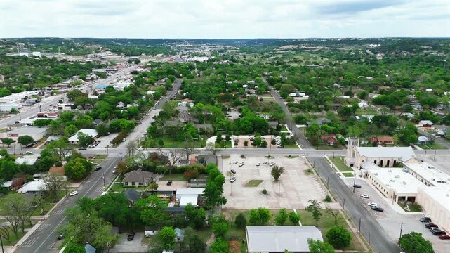 Drone view of leafy Kerrville streets and church under cloudy sky