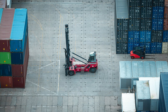 Aerial view of a reach stacker operating in a cargo containers hub with stacks of colorful shipping containers and a forklift in Poland.