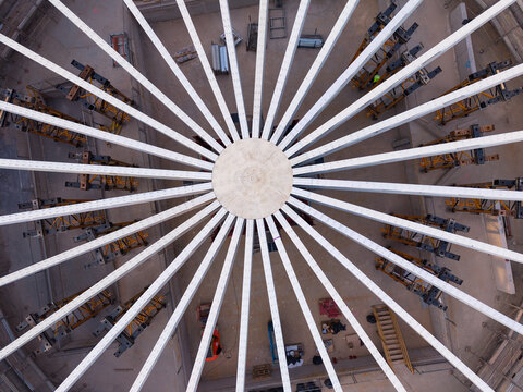 Aerial view of a circular steel roof structure under construction with radial beams and scaffolding in a construction site in Milan, Lombardy, Italy.
