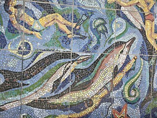 Close up detail of a mosaic mural featuring a colorful dolphin and jellyfish. Tile artwork of an underwater marine scene. Aquatic pattern texture © Elena