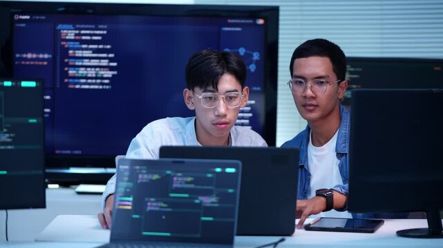 Two software developers working together on a coding project in a contemporary technology office setting