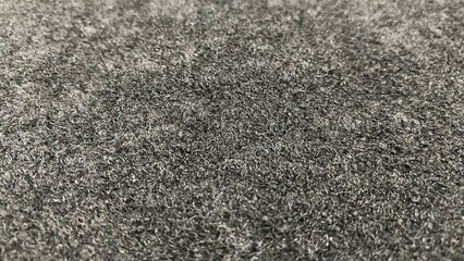 A close-up of a black or dark gray textile fabric surface with a soft, thick, and fuzzy fiber texture. © RiyanBudi