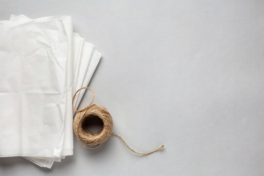 Stack of white tissue paper and a ball of jute twine seen from above