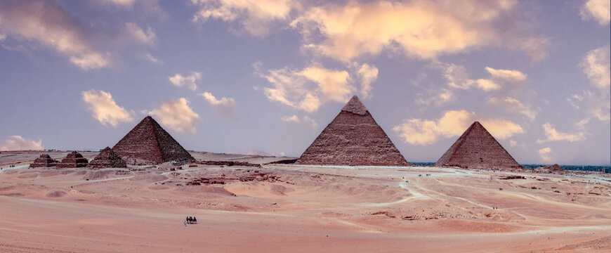 Aerial view of the iconic Pyramids of Giza rising from the vast desert landscape under a soft cloudy sky Giza, Giza Governorate, Egypt.