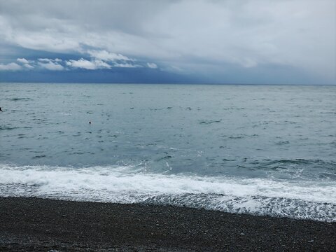 Rough sea waves crashing on a dark stone beach. Moody coastal landscape with stormy overcast sky