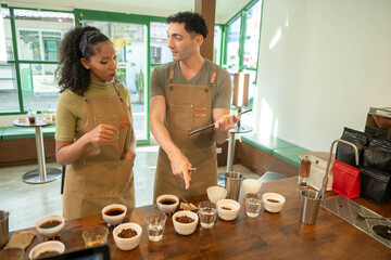 Coffee professionals evaluating brewed samples during a cupping session, with tasting cups, water...