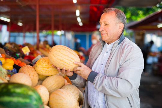 Man choosing fresh melon in market