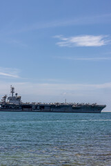 US Navy aircraft carrier USS Abraham Lincoln CVN 72 is anchored at sea. Military jets are parked on USS Abraham Lincoln. Small boat passes near USS Abraham Lincoln. © Nutchanart