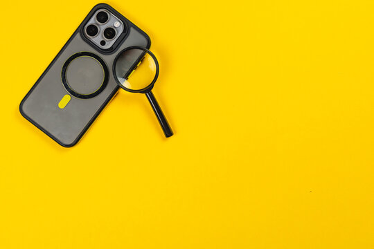 Smartphone with a magnifying glass on a bright yellow background