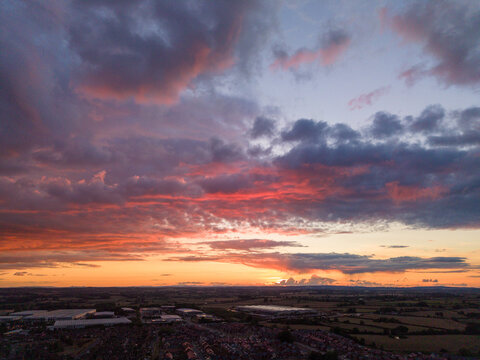 Aerial view of the town of Stafford at sunset with dramatic purple and orange clouds over residential rooftops and surrounding fields in Stafford, England, United Kingdom.