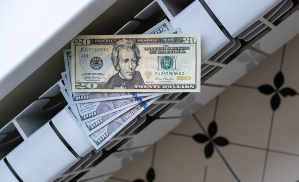 US dollar banknotes placed on a household radiator, illustrating heating costs, utility bills, taxes, inflation and financial pressure.