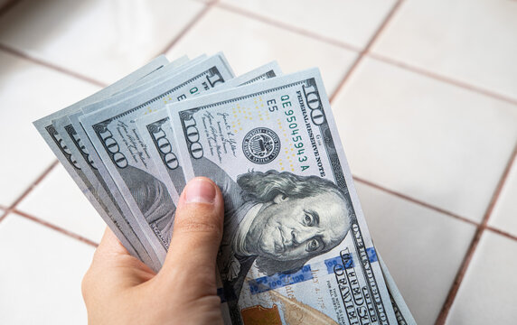 Hand holding US dollar banknotes, illustrating wealth, cash payments, financial transactions, corruption, bribery and money laundering