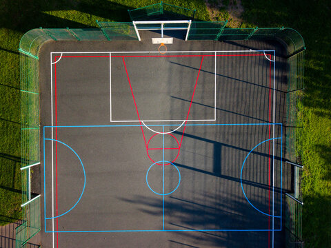 Aerial view of the basketball court at Wildwood Park with colorful red, white, and blue court markings on a dark surface surrounded by green grass, Stafford, England, United Kingdom.