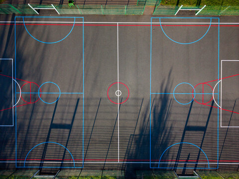 Aerial view of Wildwood Park sports court with colorful markings and long tree shadows in Stafford, England, United Kingdom.