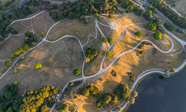 Drone aerial top down view of Olympiaberg hill and winding paths in Olympiapark, Munich, Bavaria, Germany. 