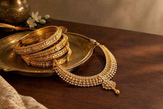 South Asian gold necklace and bangles on brass tray, jewelry arrangement