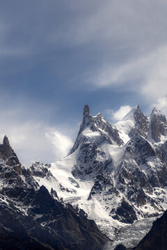 Aerial view of the dramatic granite monolith of Uli Biaho Tower rising above snow-capped peaks and glaciers under a bright sky in Skardu, Pakistan.