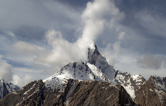 Aerial view of Uli Biaho Tower, a dramatic granite monolith mountain covered in snow and ice, rising into a cloudy sky in the Karakoram range, Skardu, Pakistan.